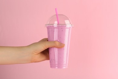 Photo of Woman with plastic cup of tasty smoothie on pink background, closeup