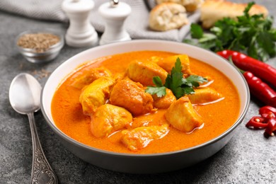 Bowl of delicious chicken curry on grey table