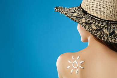 Woman with sun protection cream on her back against light blue background. Space for text