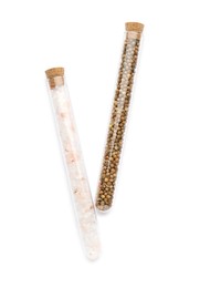 Glass tubes with pink himalayan salt and coriander seeds on white background, top view