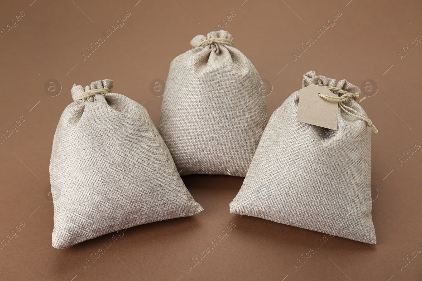 Photo of Three tied burlap bags on brown background