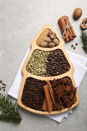 Photo of Different spices, nuts and fir branches on gray textured table, flat lay