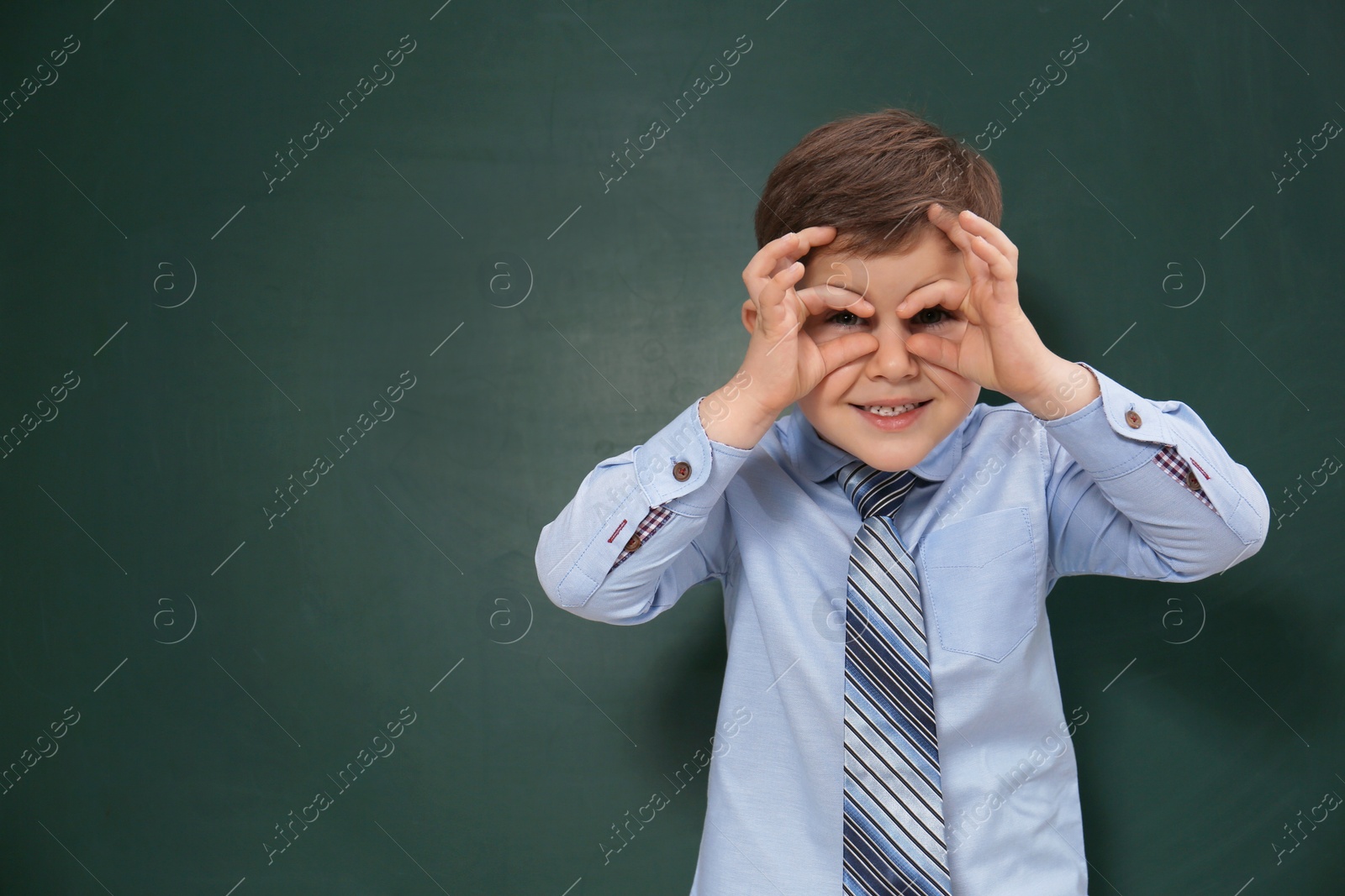 Photo of Funny little child near chalkboard, space for text. First time at school