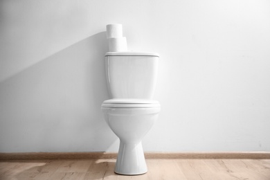 Photo of New ceramic toilet bowl near light wall