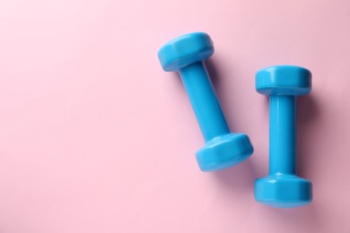 Photo of Turquoise dumbbells on pink background, flat lay. Space for text