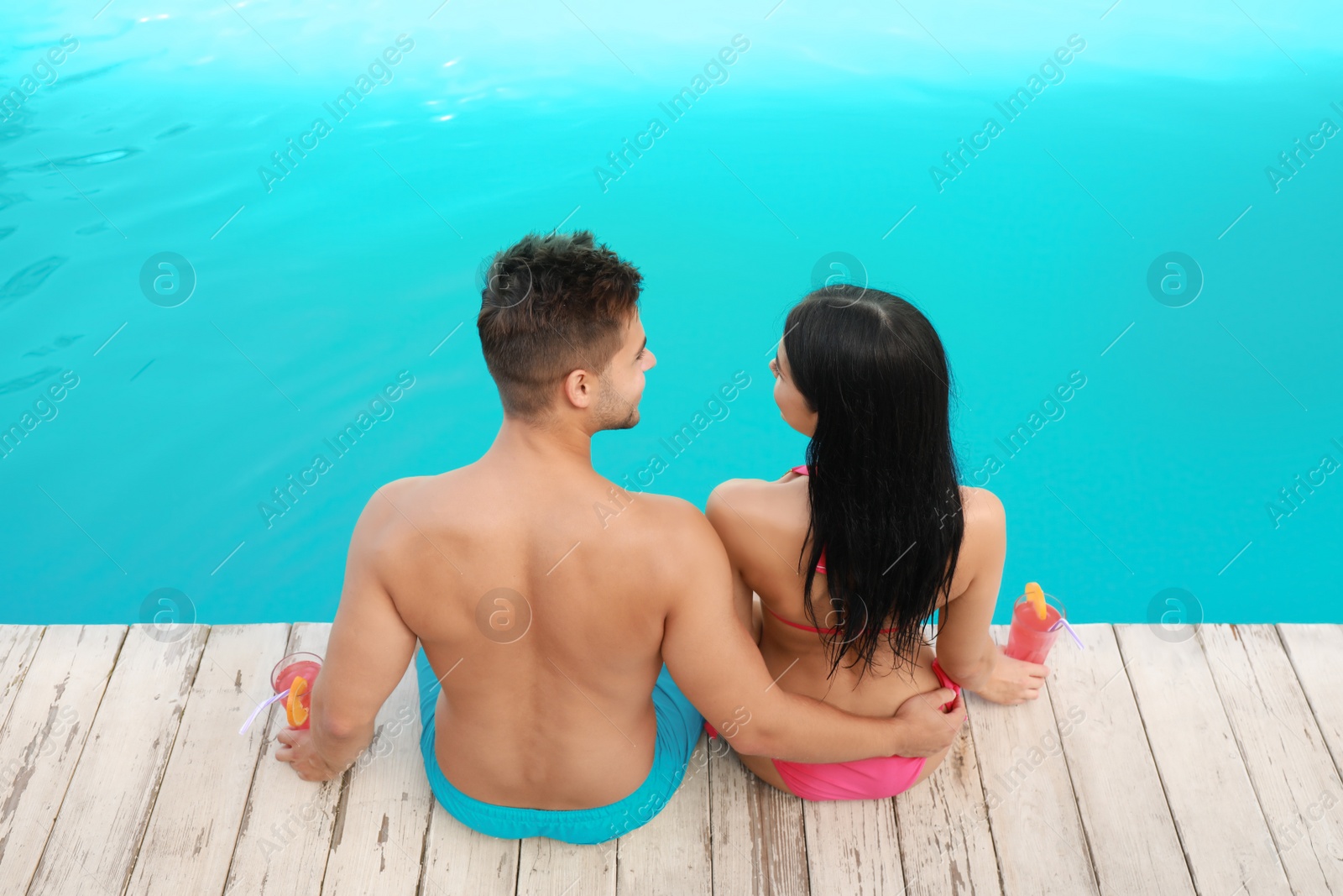 Photo of Woman in bikini with boyfriend near outdoor pool. Young couple