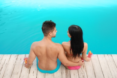 Photo of Woman in bikini with boyfriend near outdoor pool. Young couple