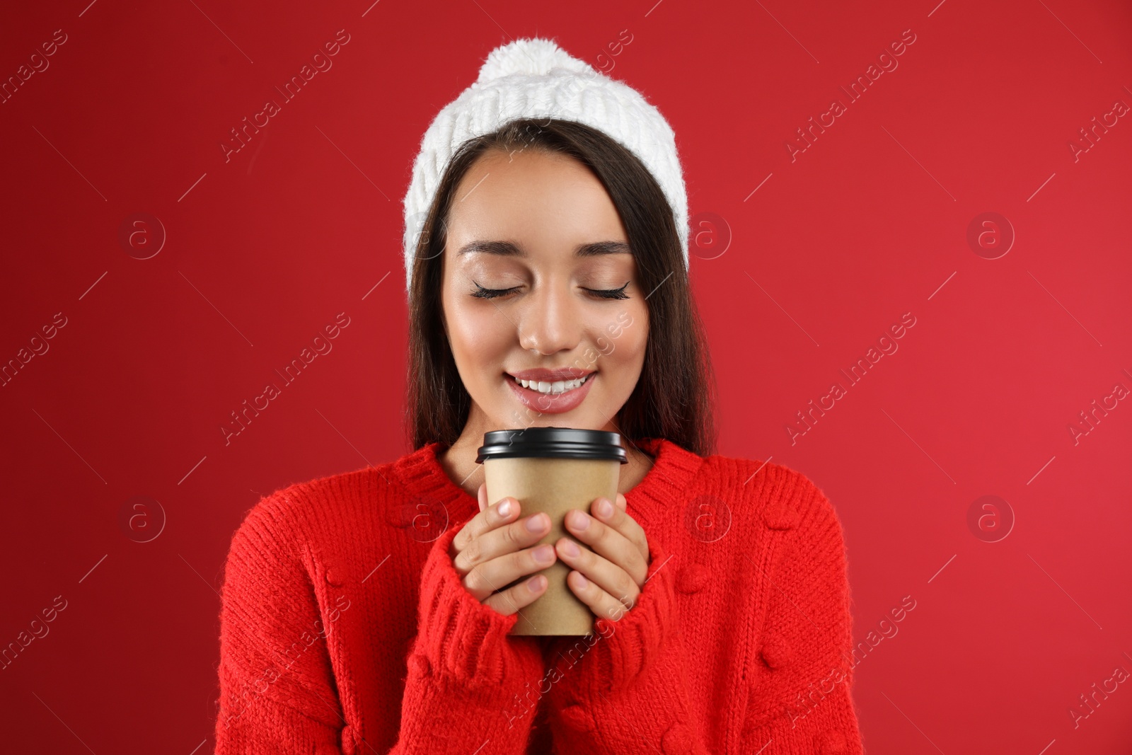 Photo of Happy beautiful woman with paper cup of mulled wine on red background