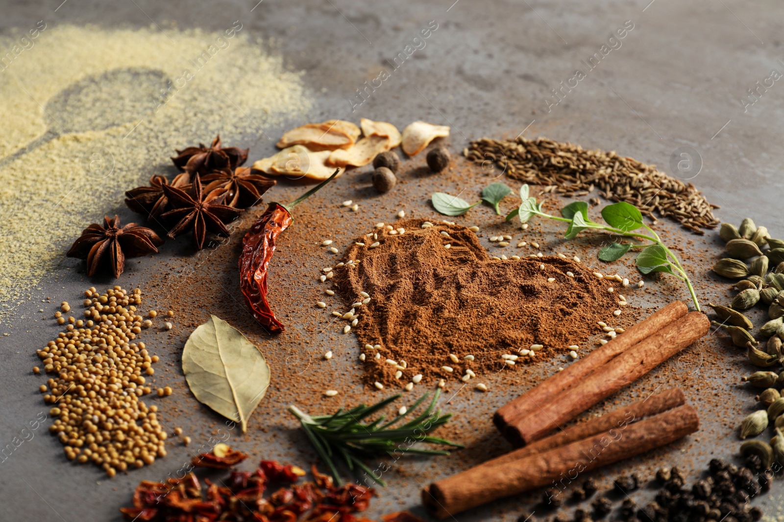 Photo of Different spices and silhouette of spoon on grey textured table, closeup