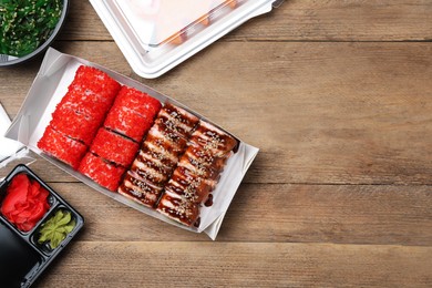 Photo of Food delivery. Delicious sushi rolls served on wooden table, flat lay with space for text