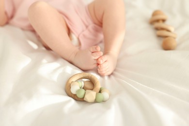Photo of Cute baby and rattle toys on sheets, closeup
