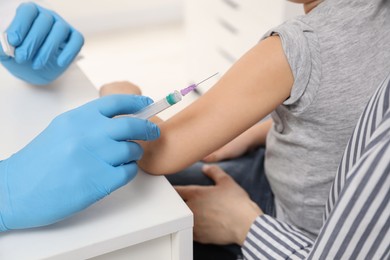 Photo of Children's hepatitis vaccination. Mother with her daughter in clinic. Doctor giving injection to little girl, closeup