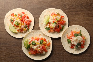 Photo of Delicious tacos with vegetables and lime on wooden table, top view