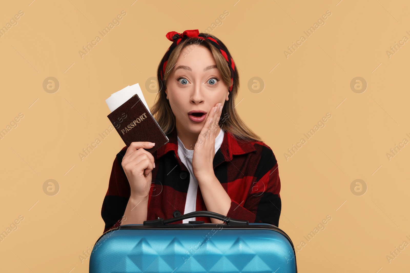 Photo of Emotional young woman with passport, ticket and suitcase on beige background