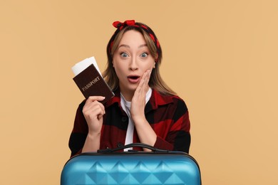 Emotional young woman with passport, ticket and suitcase on beige background