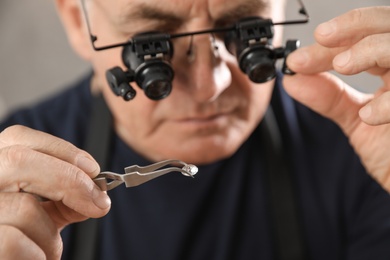 Photo of Male jeweler evaluating precious gemstone in workshop, closeup