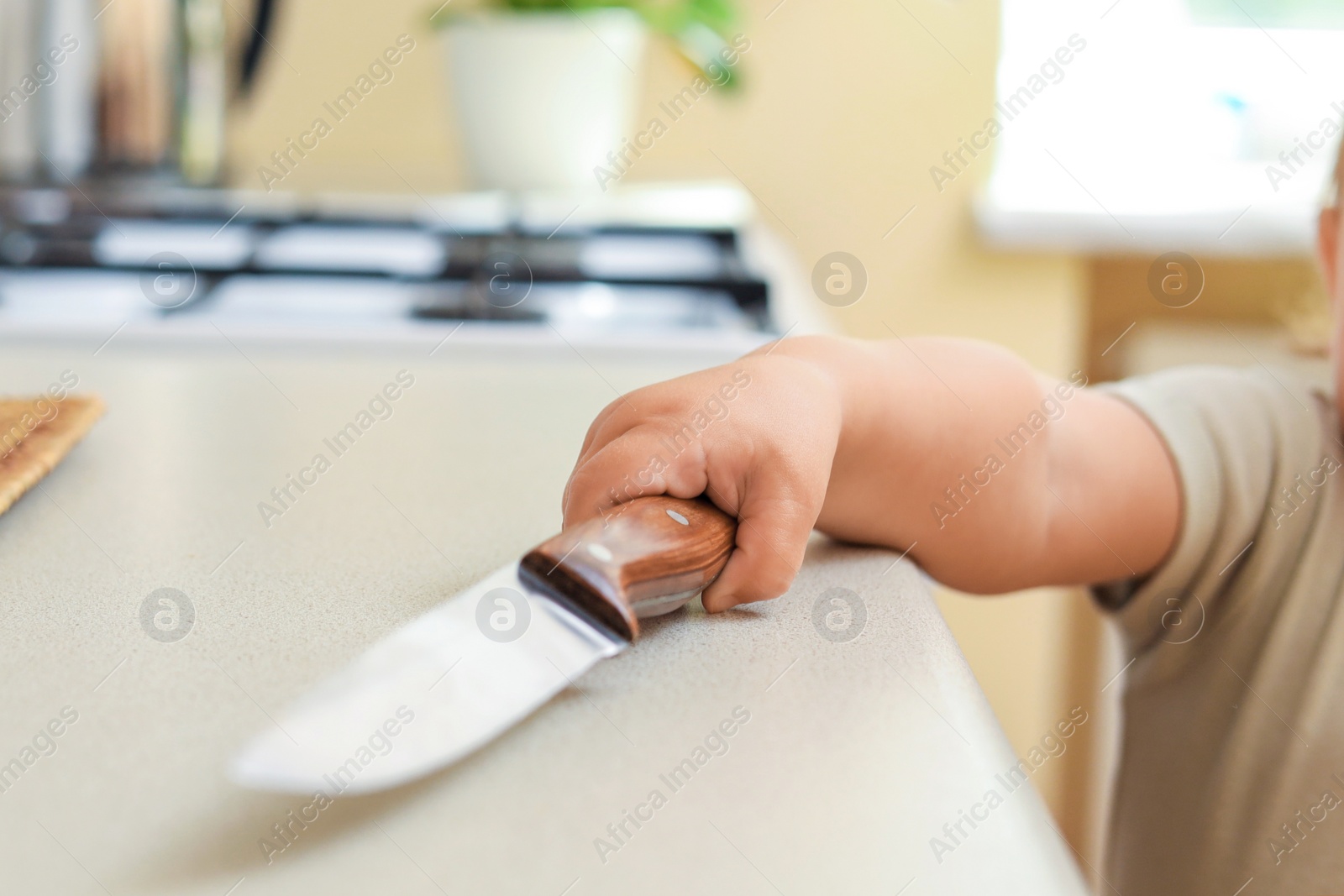 Photo of Child holding sharp knife, closeup. Dangers in kitchen