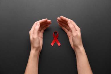 Photo of Woman with red awareness ribbon on black background, top view. World AIDS disease day