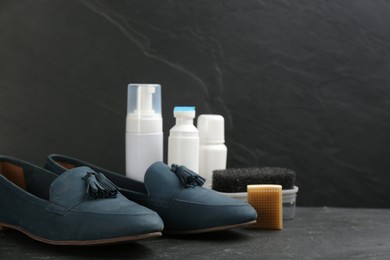Photo of Stylish footwear with shoe care accessories on black table