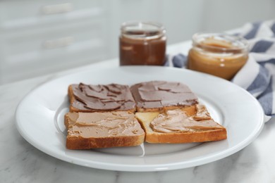 Toasts with tasty nut butter on marble table, closeup