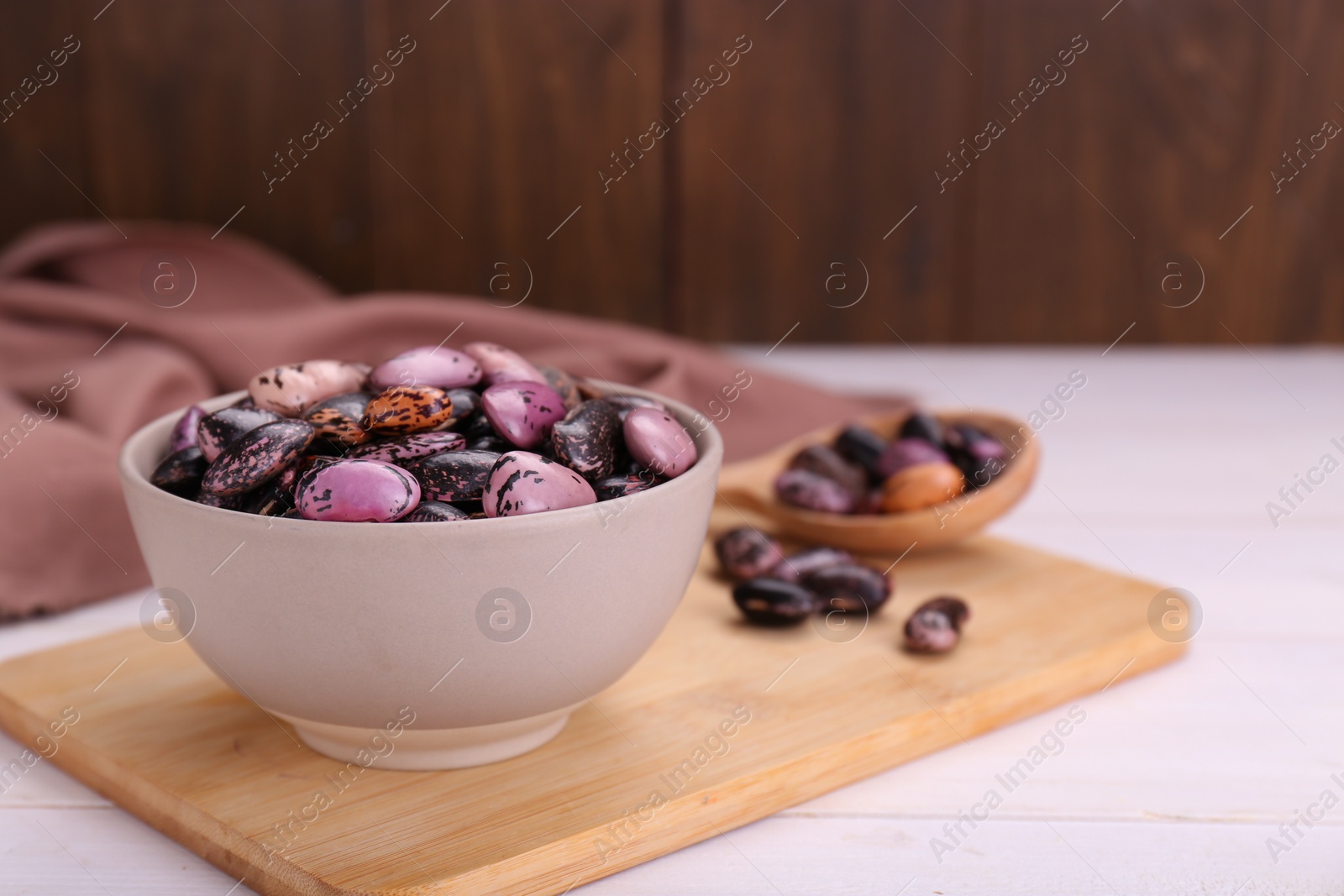 Photo of Bowl with dry kidney beans on white wooden table. Space for text