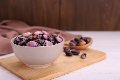 Bowl with dry kidney beans on white wooden table. Space for text