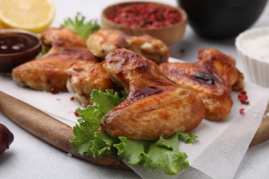 Photo of Fresh marinated chicken wings and lettuce on light table, closeup