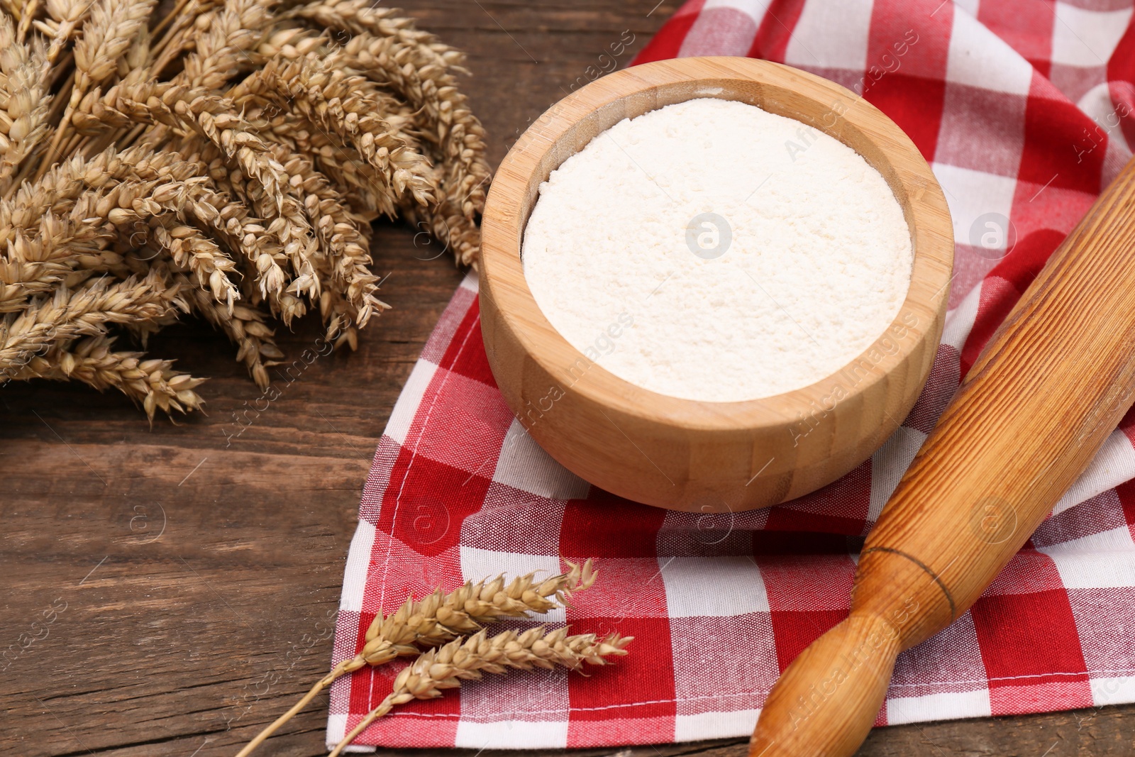 Photo of Ears of wheat and flour on wooden table