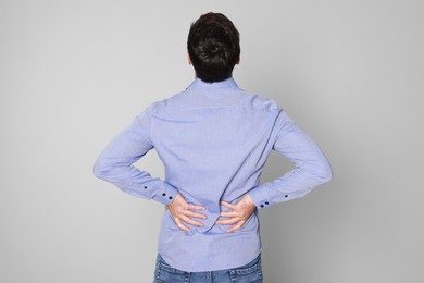 Photo of Man suffering from pain in back on light background. Arthritis symptoms