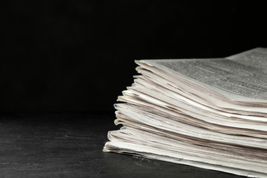 Stack of newspapers on dark stone table, space for text. Journalist's work