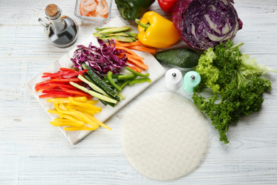 Photo of Dry rice paper and ingredients on white wooden table, flat lay