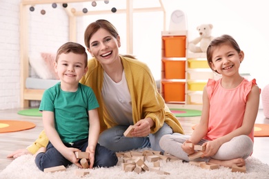 Nanny and little children playing at home