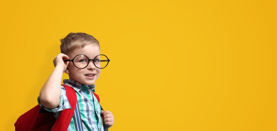 First time at school. Cute little child wearing glasses on yellow background, space for text. Banner design