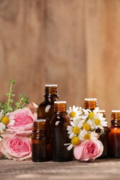 Bottles with essential oils, thyme and flowers on wooden table. Space for text