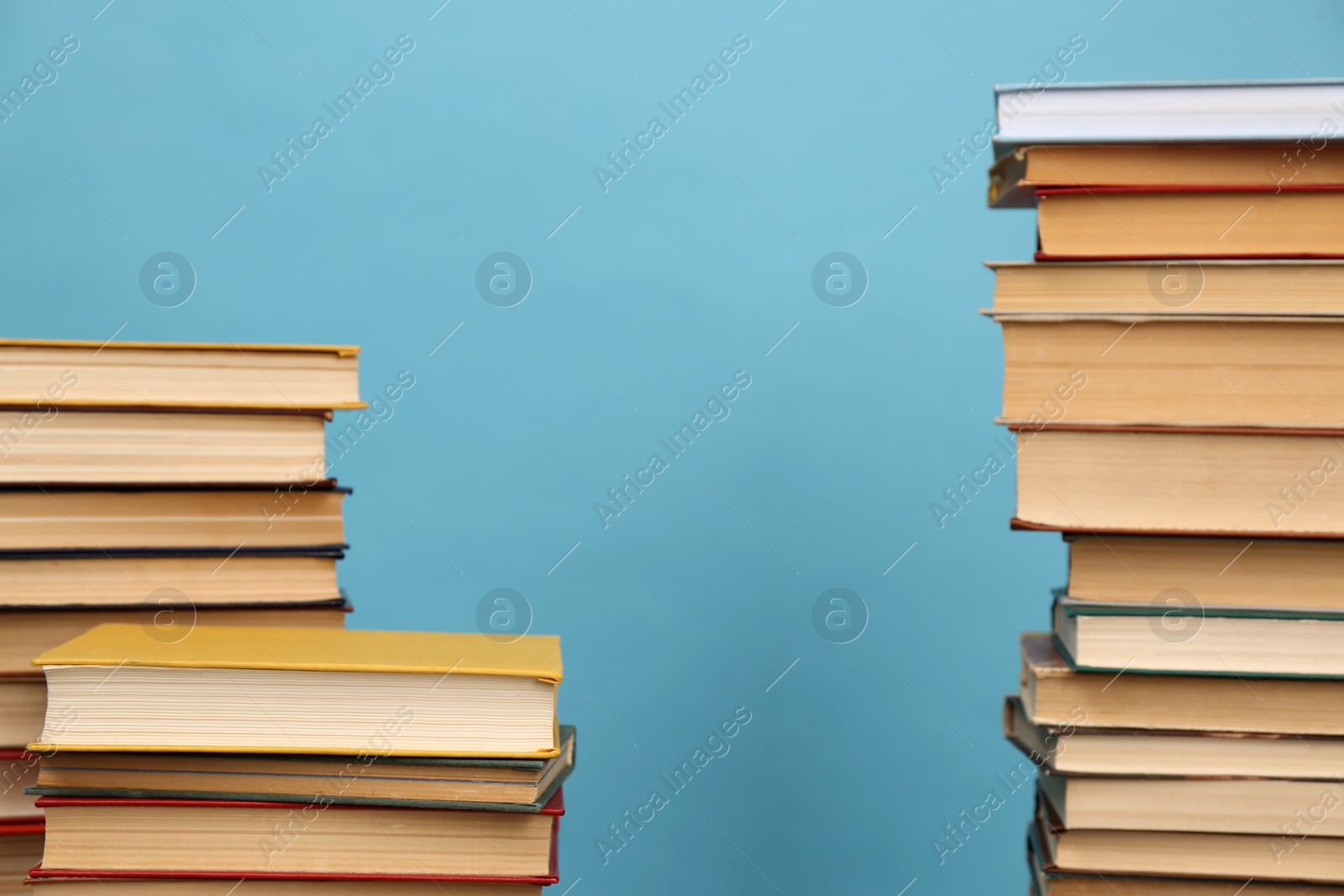 Photo of Many hardcover books on turquoise background, space for text. Library material