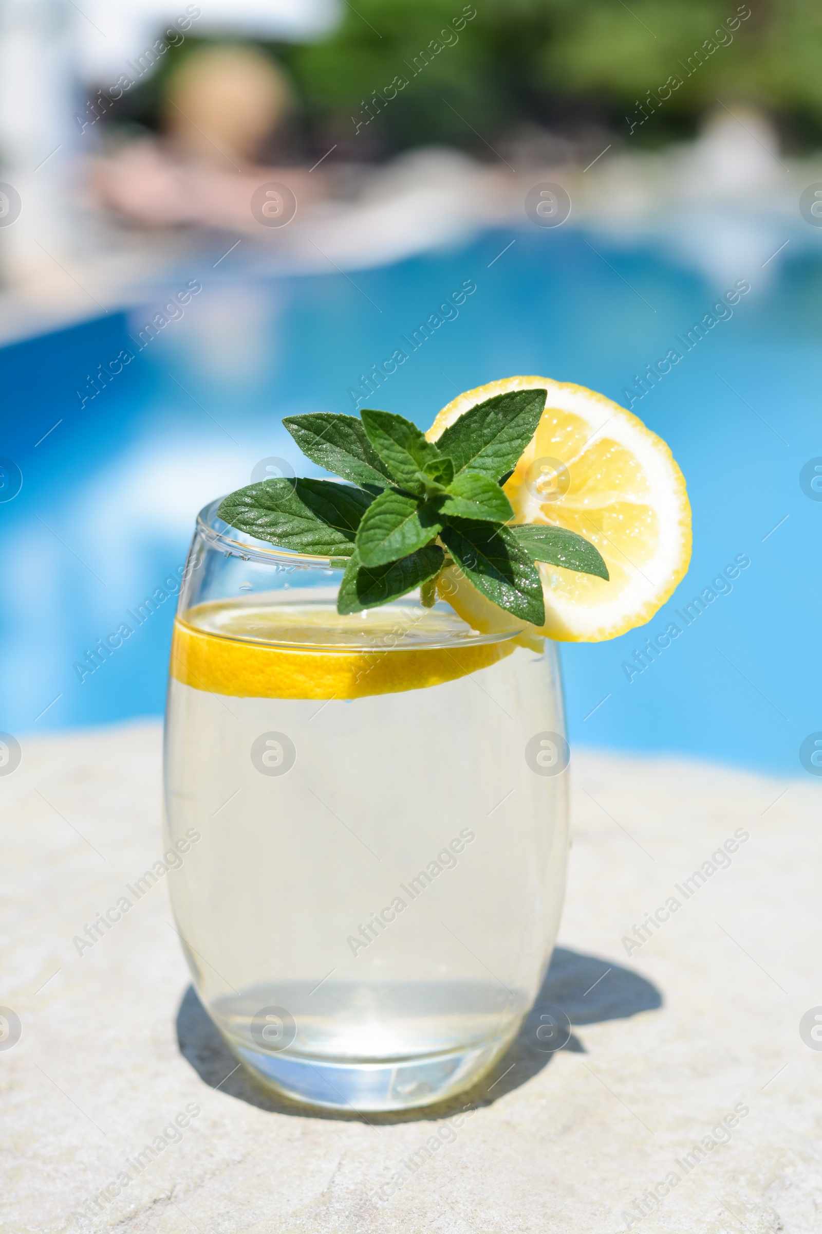 Photo of Refreshing water with lemon and mint on rock outdoors