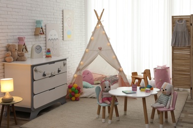 Photo of Cute child's room interior with toys and play tent