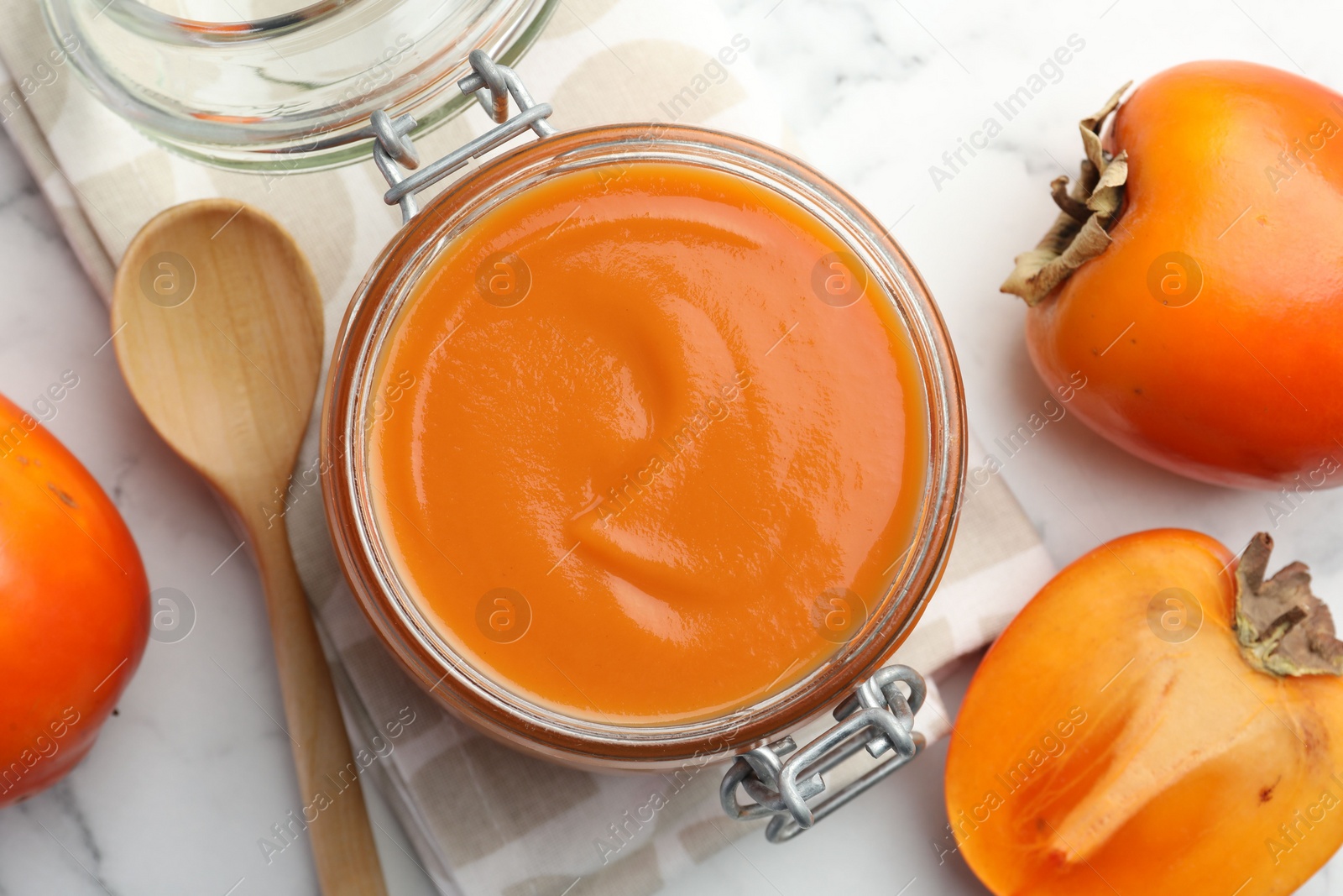 Photo of Delicious persimmon jam and fresh fruits on white table