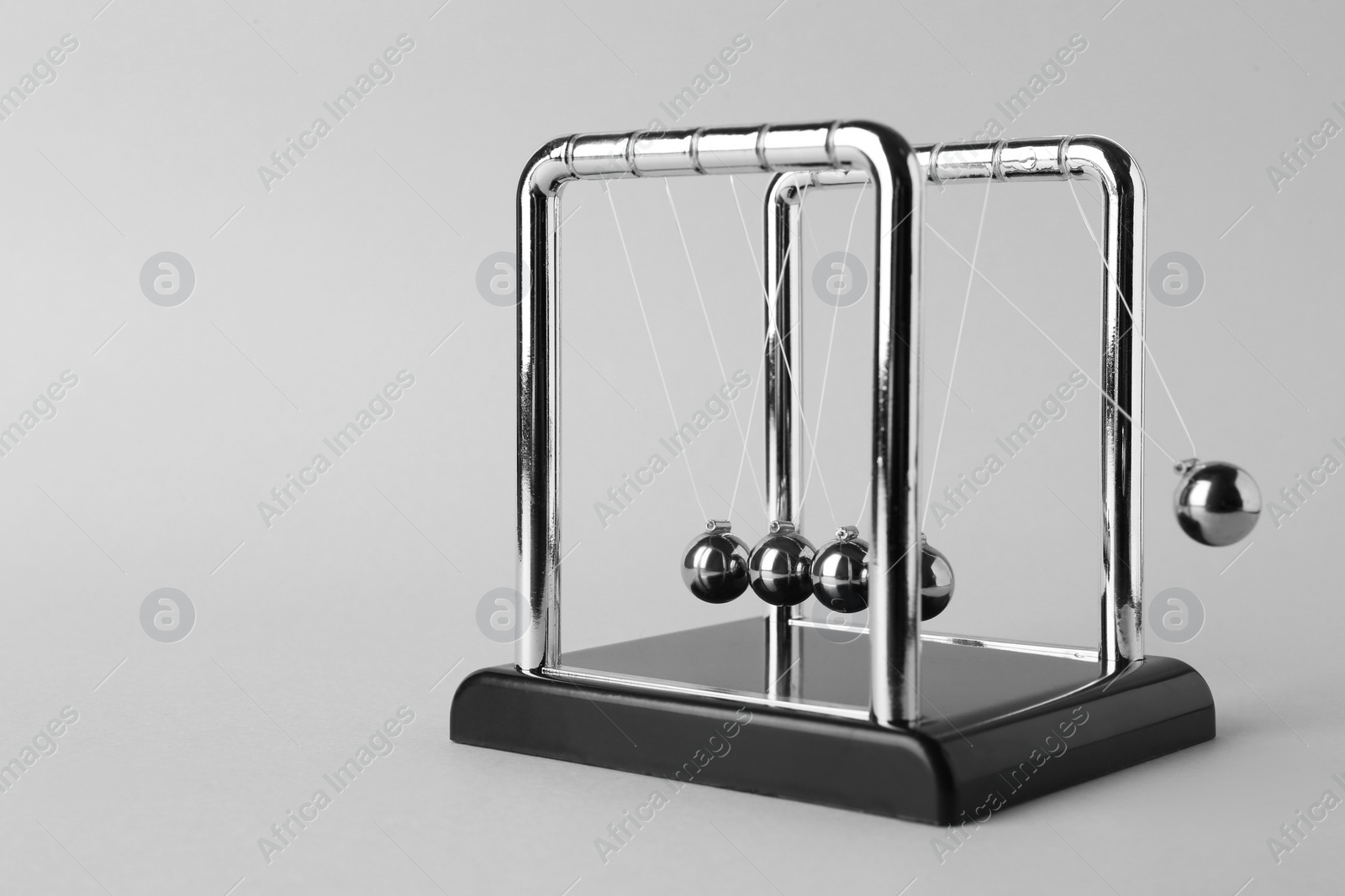 Photo of Newton's cradle on light background, space for text. Physics law of energy conservation