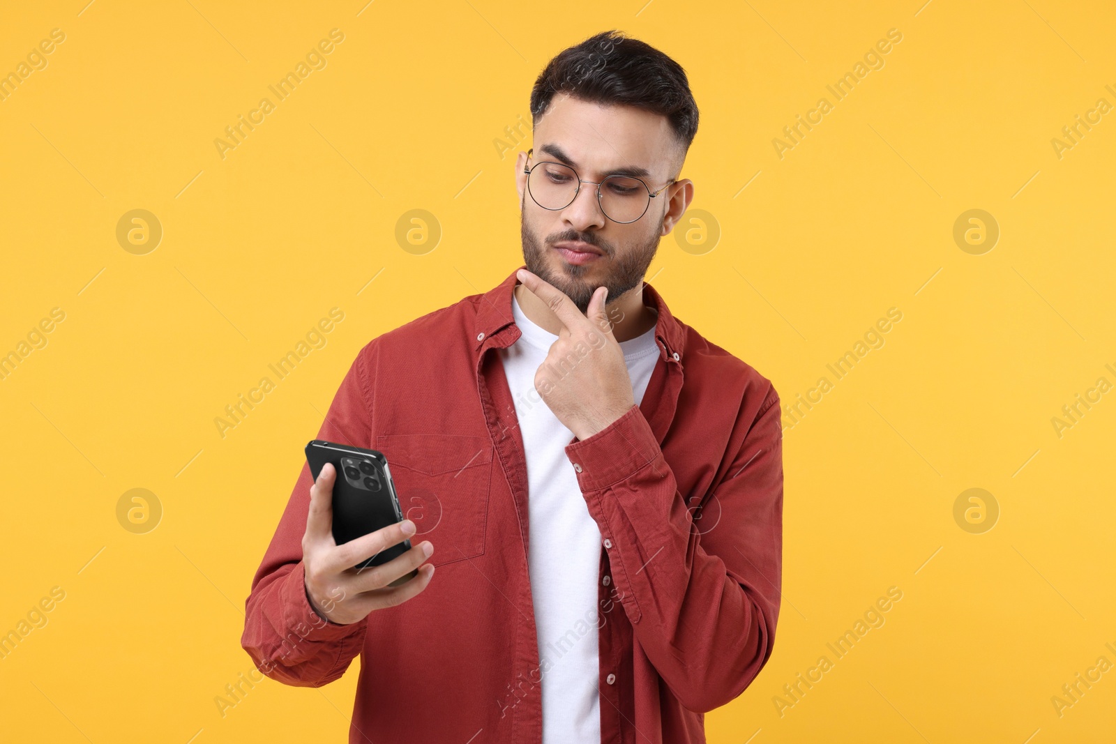 Photo of Handsome young man using smartphone on yellow background