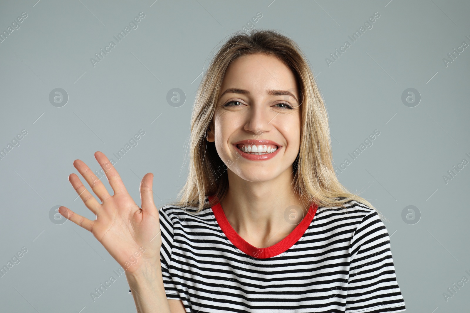 Photo of Woman showing number five with her hand on light grey background