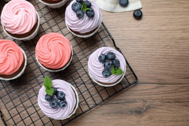 Photo of Sweet cupcakes with fresh blueberries on wooden table, flat lay. Space for text