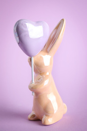 Photo of Bunny ceramic figure as Easter decor on violet background