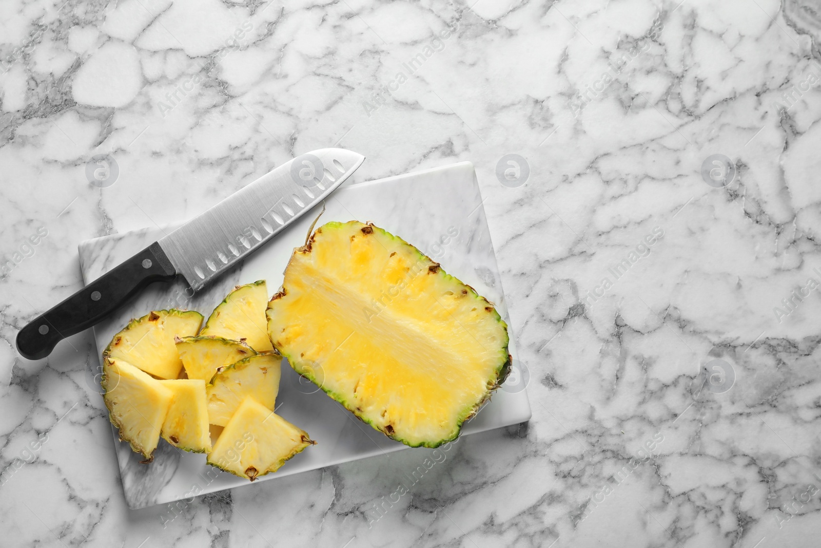 Photo of Board with fresh sliced pineapple and knife on marble background, top view