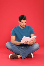 Handsome man reading book on color background, space for text