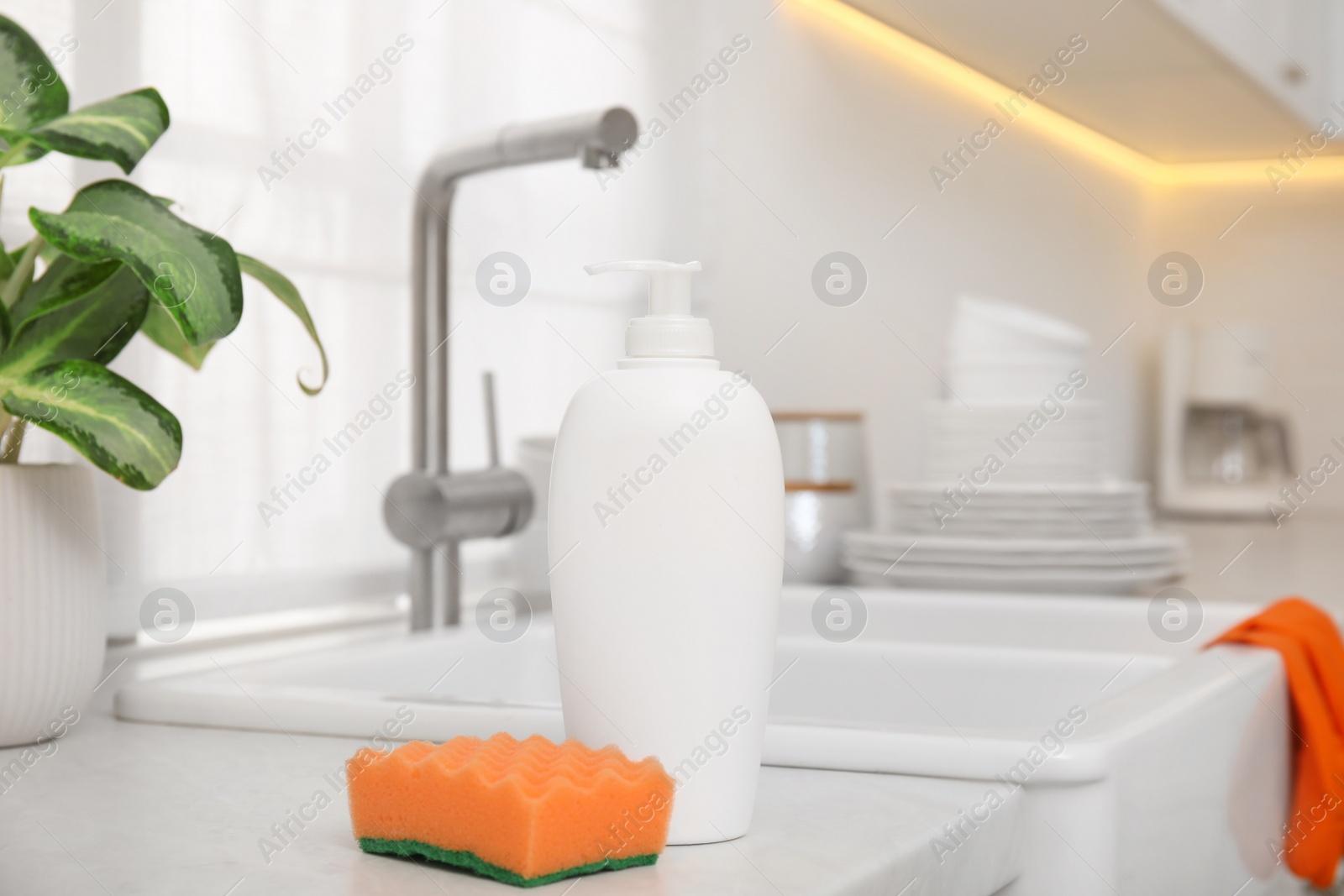 Photo of Cleaning product with sponge near sink in stylish kitchen