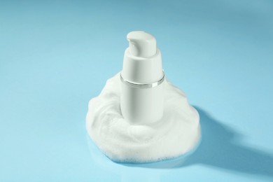 Photo of Bottle with cleansing foam on light blue background, closeup. Cosmetic product