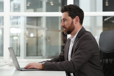 Man working on laptop at white desk in office