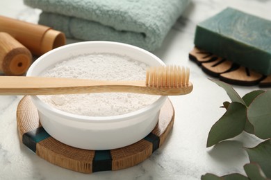 Photo of Tooth powder and brush on white marble table, closeup
