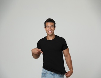 Photo of Handsome young African-American man in blank t-shirt on light background. Space for design